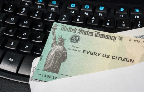 US Treasury concept check to illustrate coronavirus stimulus payment on keyboard used for working from home