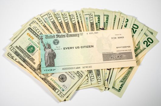 Stack of 20 dollar bills with US Treasure illustrative check to illustrate coronavirus stimulus payment on white background