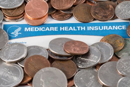 USA Medicare health insurance card with piles of loose change and cash to show funding crisis