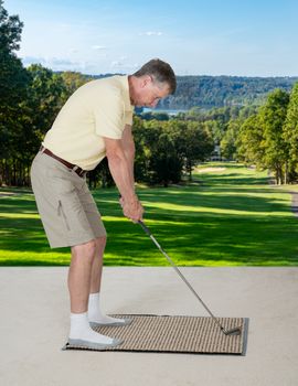 Senior caucasian man practicing his golf grip and swing on a mat in bedroom at home and imagining he was outside on a real golf course