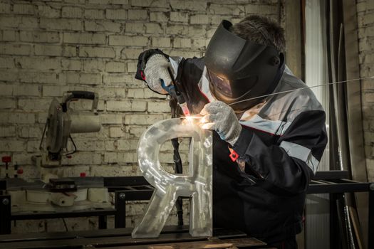 Welder welding a metal part in an industrial environment, wearing standard protection equipment. Sparks flying, fumes, industrial background