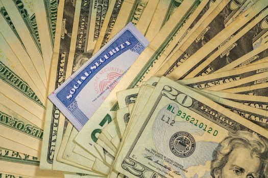 Thousands of US dollars laid out in a flat background perspective with the focus on a social security card