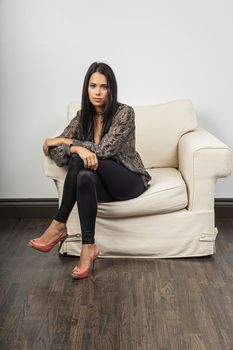 millenial woman, wearing stylish clothes, sitting on a white couch