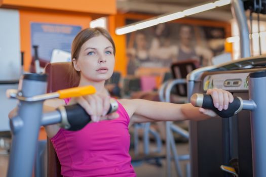 Woman doing fitness training on hand extension push machine with weights