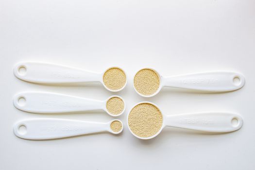 A top general view of some measurement baking spoons with yeast on them