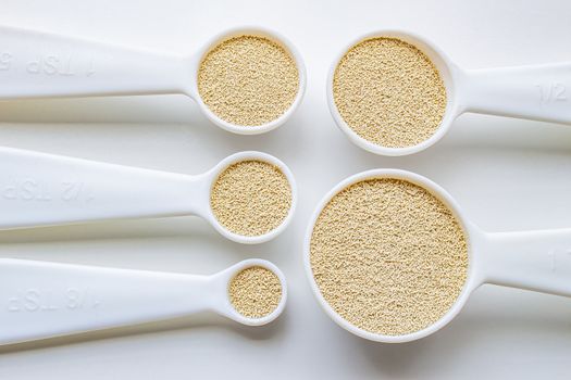 A close view of some measurement baking spoons with yeast on them