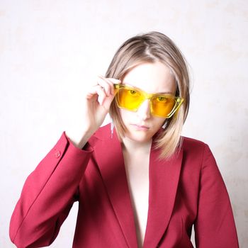 Bright portrait of a girl in yellow glasses. Serious facial expression