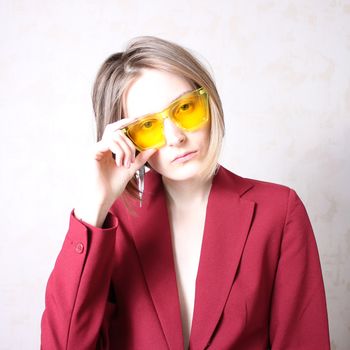 Bright portrait of a girl in yellow glasses. Serious facial expression