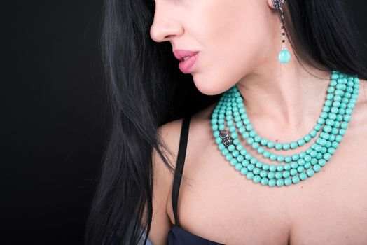 Young woman with beautiful jewelry on black background, closeup