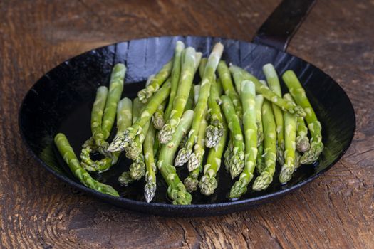 fresh green asparagus in a pan on dark wood