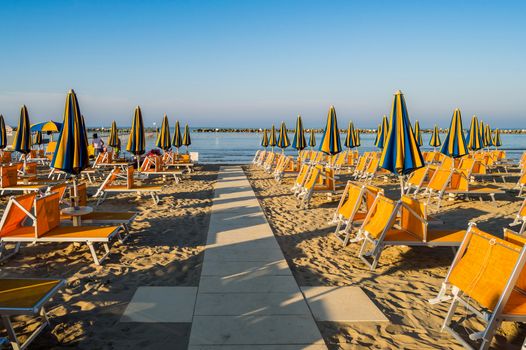 Rows of orange umbrellas and deckchairs on the beach of Igea Marina near Rimini