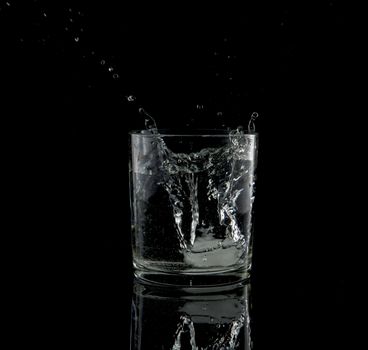 almost black and white of a splash from a falling ice cube in glass of water