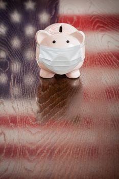 Piggy Bank Wearing Medical Face Mask With American Flag Reflecting on Table.