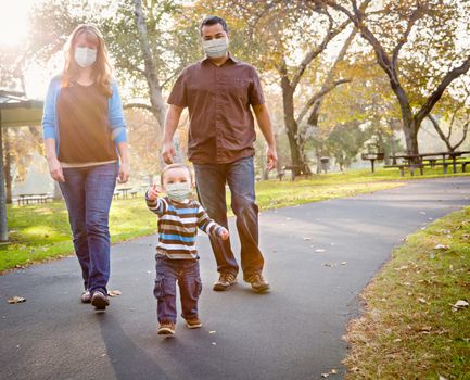 Happy Mixed Race Ethnic Family Walking In The Park Wearing Medical Face Mask.