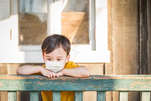 Young Mixed Race Chinese and Caucasian Boy Playing Alone Wearing Medical Face Mask Outside.
