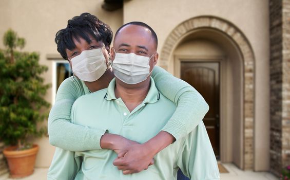 Loving African American Couple Hugging Wearing Medical Face Masks In Front of House.