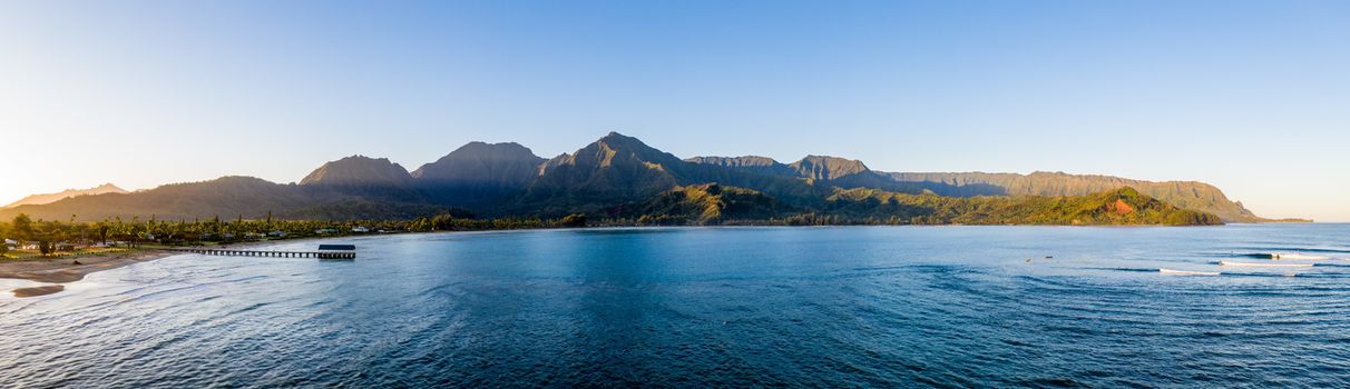 Aerial panoramic image at sunrise off the coast over Hanalei Bay and pier on Hawaiian island of Kauai