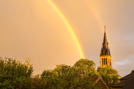 Rainbow over the Church of Saint-Mard with the bell tower struck by the sunlight