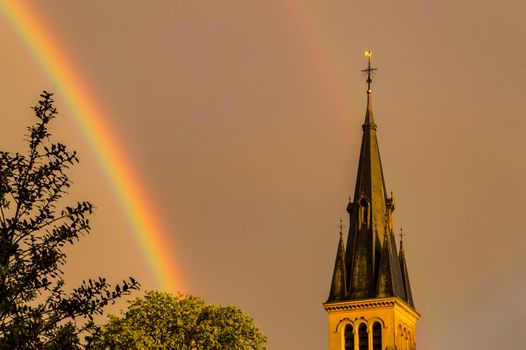 Rainbow over the Church of Saint-Mard with the bell tower struck by the sunlight