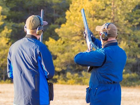 Men practicing of shooting outdoor. Shooting Center in Estonia, Tallinn. Forest on the background. Autumn season