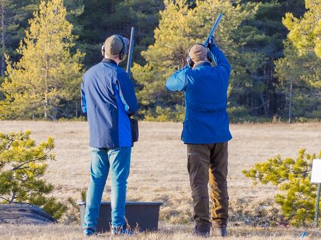 Men practicing of shooting outdoor. Shooting Center in Estonia, Tallinn. Forest on the background. Autumn season