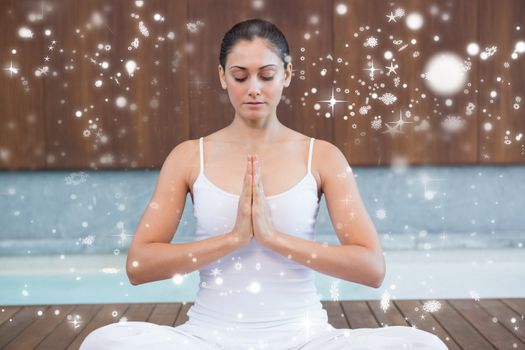 Peaceful woman in white sitting in lotus pose against snow falling