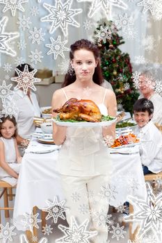 Mother showing turkey for Christmas dinner against snow falling