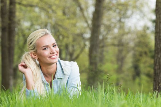 Happy smiling young woman laying on the green grass