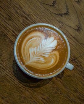 Rosette latte art on cafe latte on wooden table