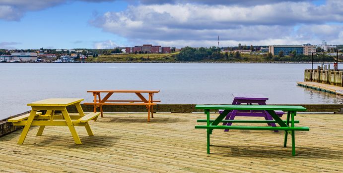 Four colorful picnic benches on a dock of treated lumber at a marina