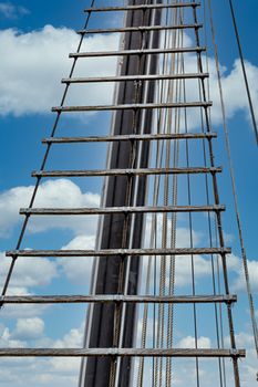Wood and rope ladder up a tall mast of a sailing ship