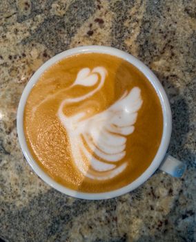 Swan latte art on cafe latte on stone table