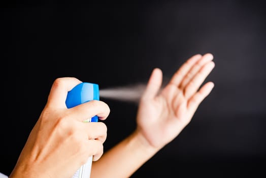 Closeup Hand Asian young woman applying spray pump dispenser sanitizer alcohol on hand wash cleaning, hygiene prevention COVID-19 or coronavirus protection concept, isolated on black background