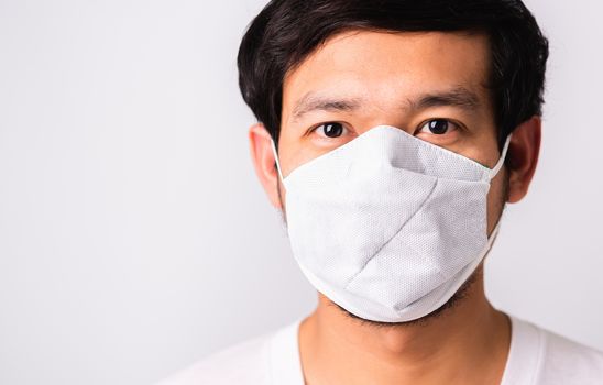 Closeup Asian handsome Man wearing surgical hygienic protective cloth face mask against coronavirus, studio shot isolated white background, COVID-19 medical concept