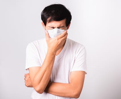 Asian handsome Man wearing surgical hygienic protective cloth face mask against coronavirus he sneeze hand close mouth, studio shot isolated white background, COVID-19 medical concept