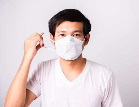 Closeup Asian handsome Man wearing surgical hygienic protective cloth face mask against coronavirus, studio shot isolated white background, COVID-19 medical concept