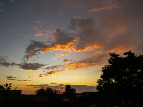 Sunset view with golden clouds and woods silhouetted in the foreground.