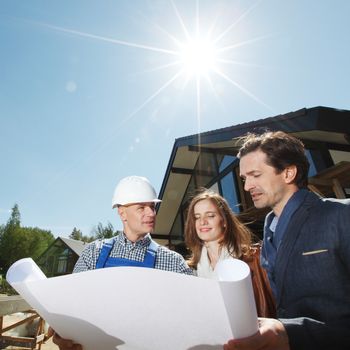 Foreman showing house design construction plan to a happy young couple new house real estate concept