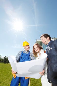 Foreman showing house design construction plan to a happy young couple new house real estate concept