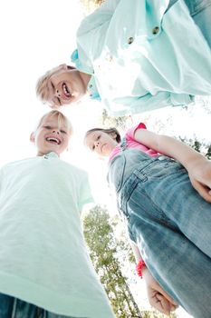 Group of three children friends outdoors looking down and smiling