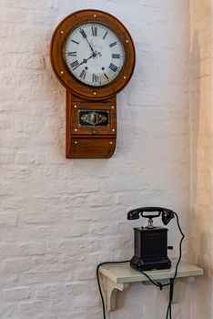 Antique wooden telephone and clock on white wall
