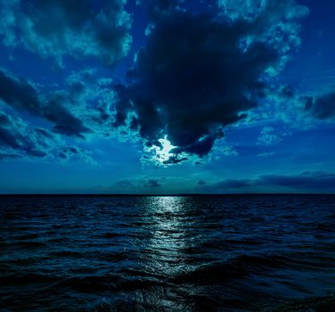 This photo illustration of a deep blue moonlit ocean at night with calm waves would make a great travel background for any coastal region or vacation.
