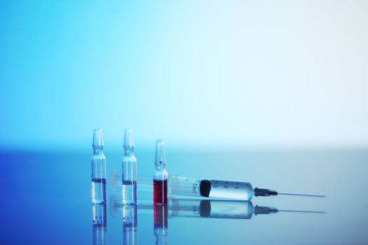 Syringe and ampoules on glowing blue reanimation light background