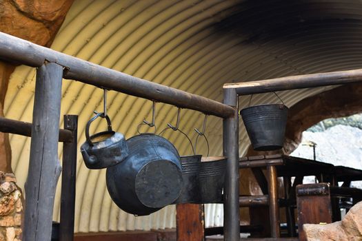 Fire buckets for water heating hanging on a handrail at an outdoors trail campsite, Rustenburg, South Africa