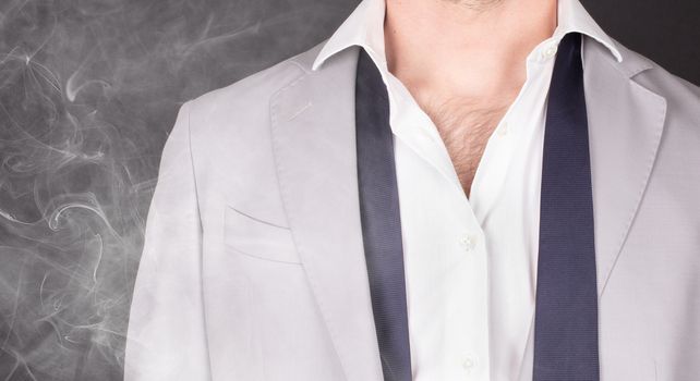 Man in a grey suit with blue tie, standing in smoke, close-up