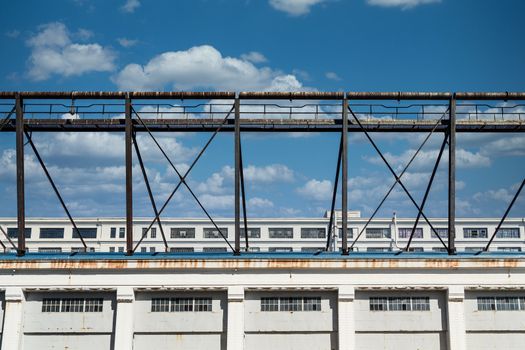 An old rusty metal walkway above an old white building with windows