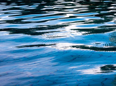 Reflection of sky on the moving water surface in the pool