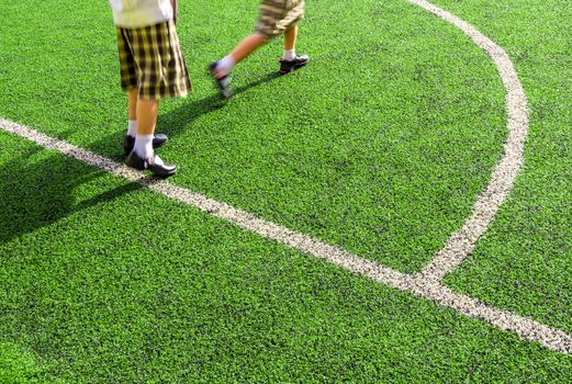 Children play on the artificial turf of the school