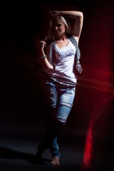 young, blonde girl in jeans clothes on a dark background