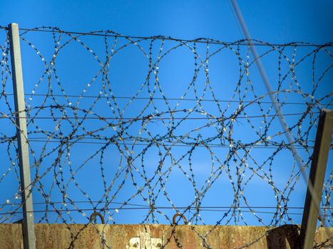 Restricted Area Barbed Fence. Concrete wall, against the backdrop of barbed wire, the concept of prison, salvation, Refugee, lonely, space for text. Protected object, no unauthorized entry.